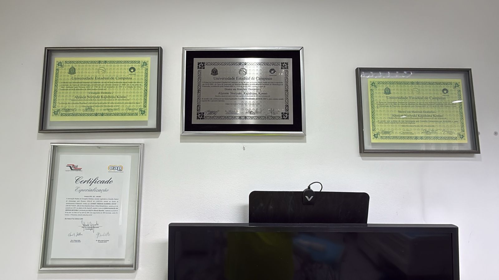 Diplomas e certificações do Dr. Alysson na parede da clínica